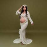 Vestido largo y ajustado de corte sirena con manga larga y detalle fruncido anudado en la zona delantera; tejido ligero y algo translúcido con volantitos en los bordes color blanco